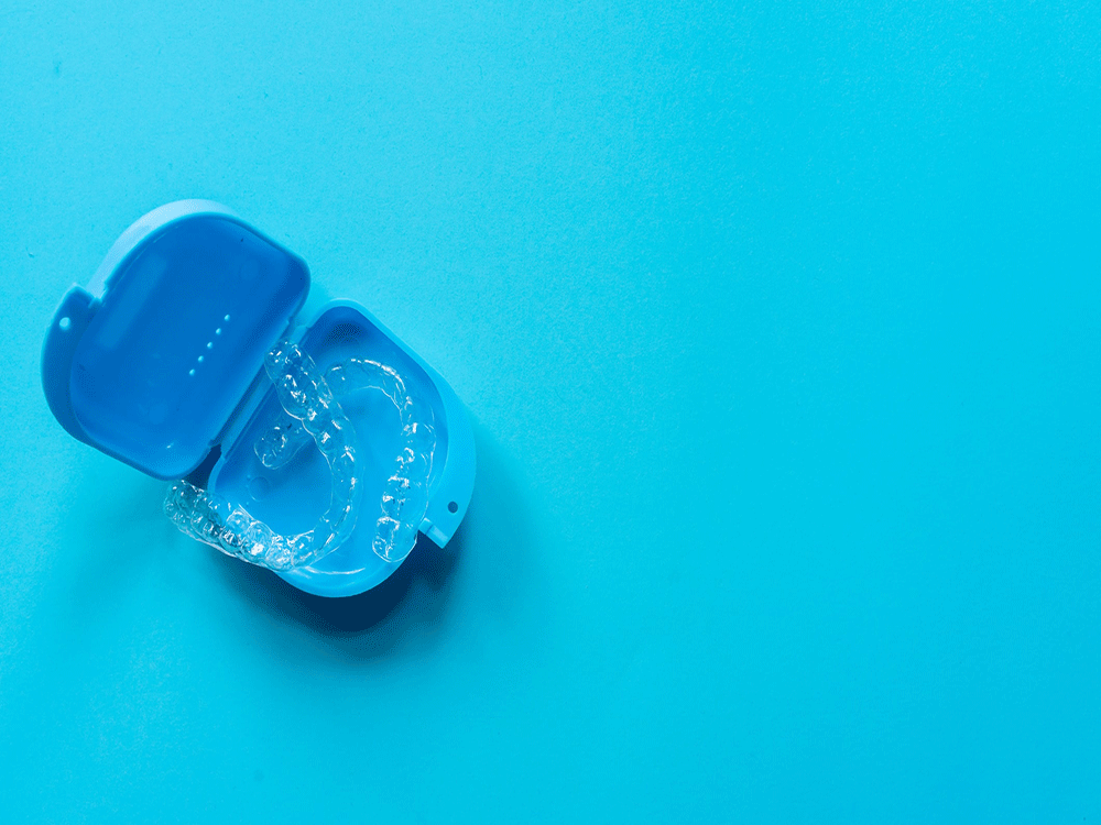 Invisalign clear aligners sitting in a blue box against a blue background.
